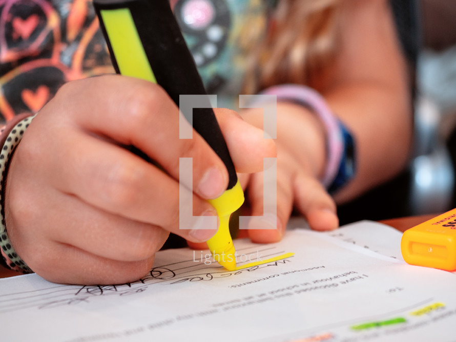 a girl uses a highlighter while doing school homework