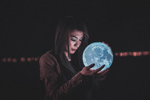 a woman holding a glowing orb of the moon 