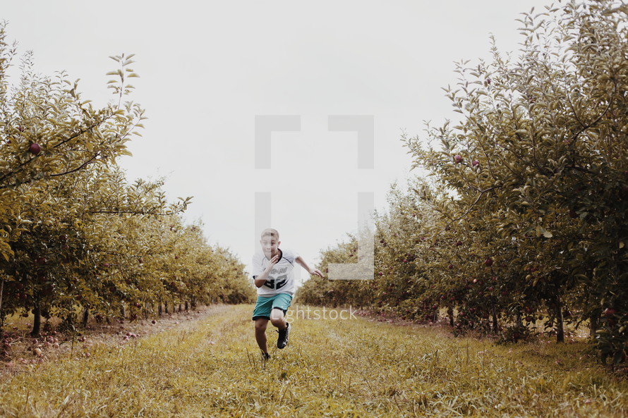boy running in an orchard 