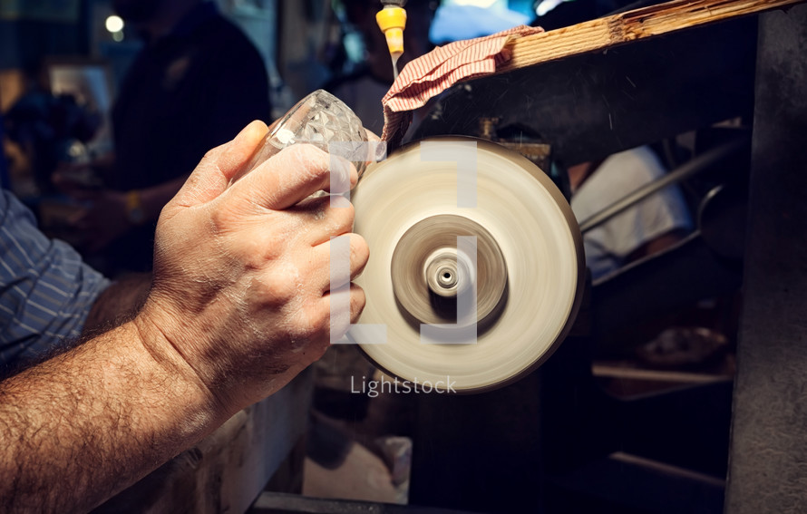 Close up of hands of the craftsman during sanding of a crystal ashtrays