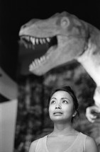 woman standing under a dinosaur at a museum