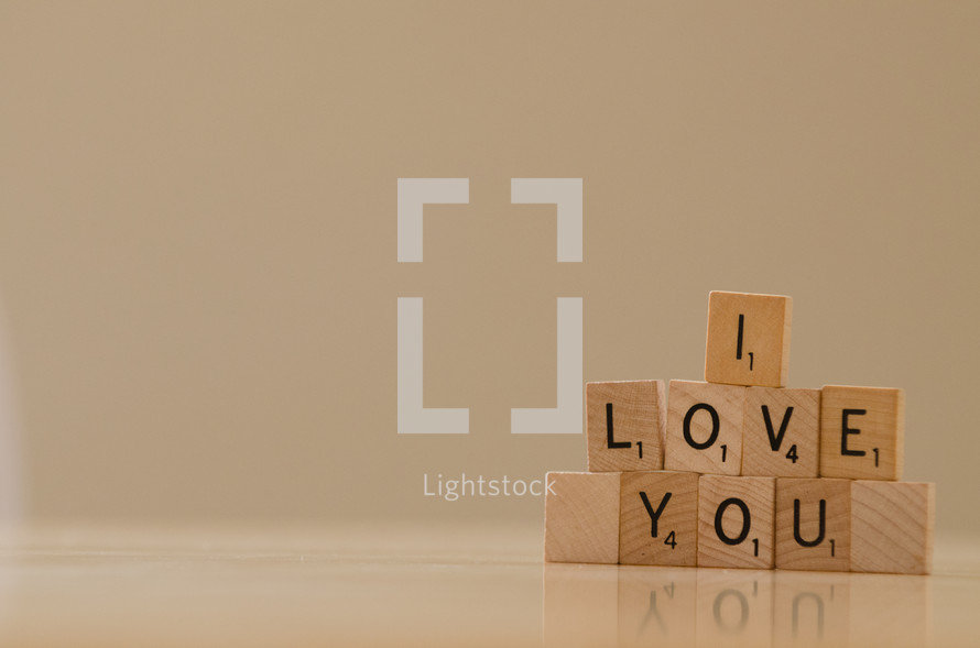 "I love you" spelled in stacked scrabble tiles.