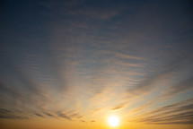 wispy clouds in a blue sky at sunrise 