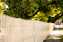 white picket fence and sidewalk in a neighborhood 