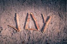 word joy made with sticks in ashes