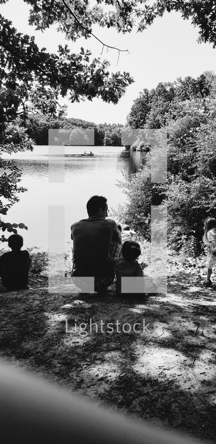 father and his kids sitting on a shore 