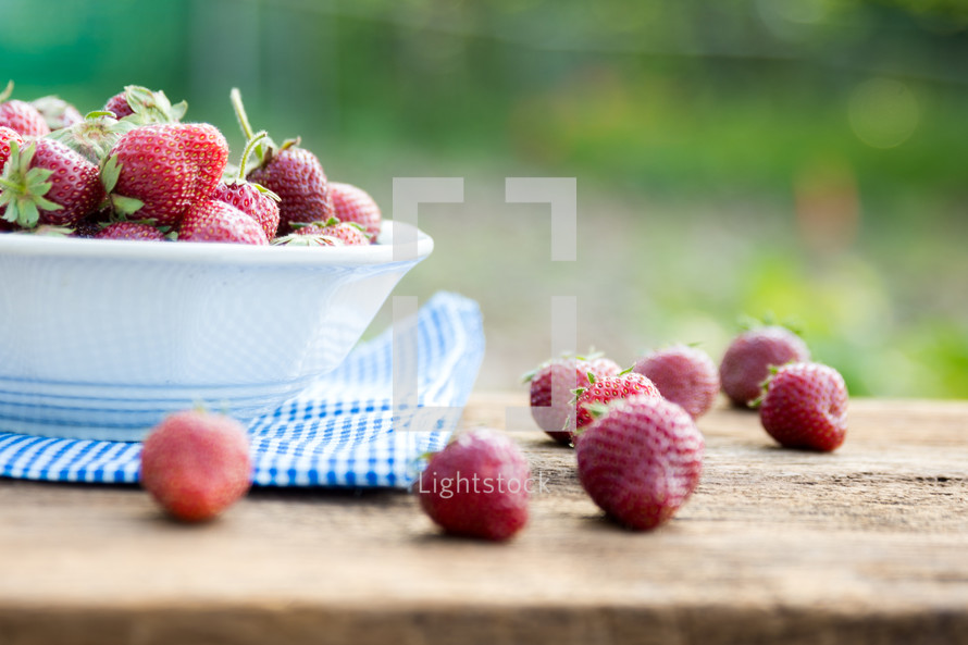 a bowl of fresh strawberries outside
