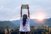 Young woman holding and lift up bible to sky at outdoors,christian concept.