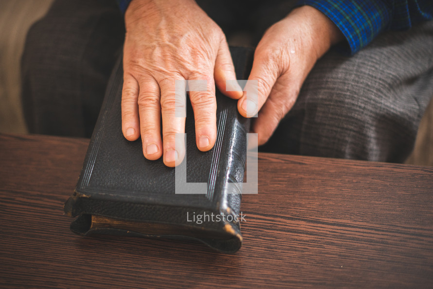 an elderly man with his hand on a Bible 
