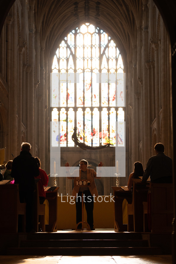 Church choir practice in a cathedral with light shining through a beautiful stained glass window