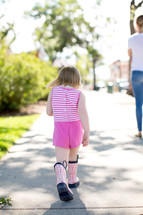 Little girl walking outside in pink rain boots 