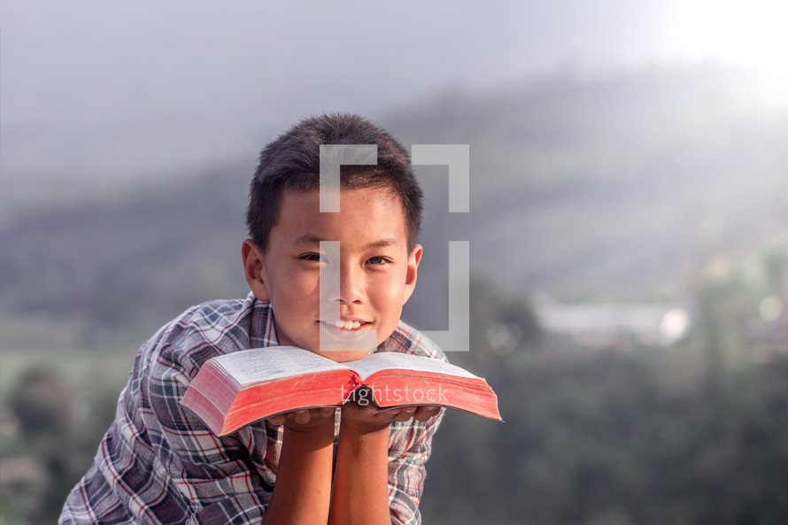 a child holding a Bible under his face 