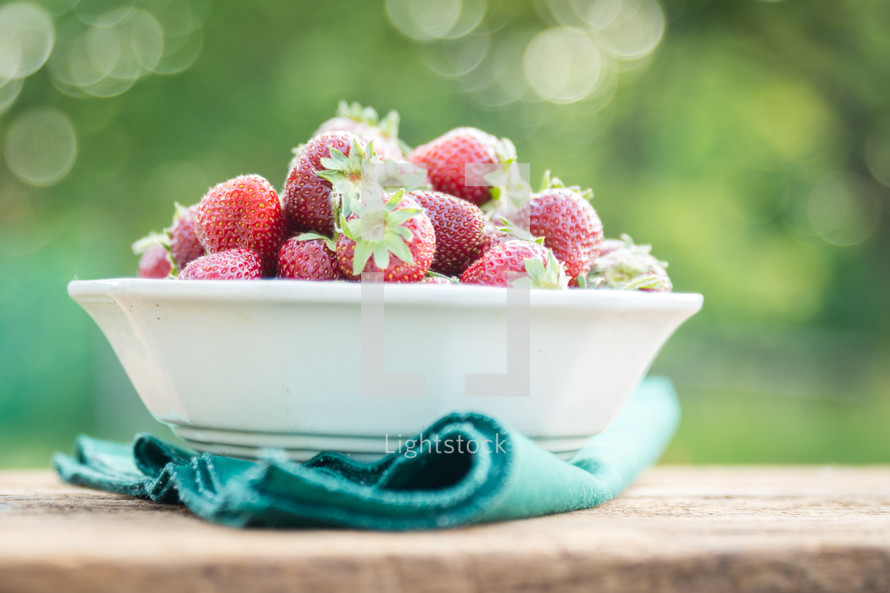 a bowl of fresh strawberries outside