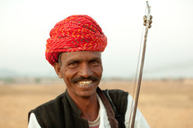 A smiling Indian man in a red turban.