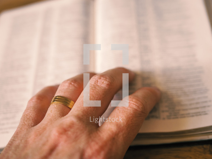 hand on the pages of a Bible 
