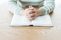 praying hands over a Bible 