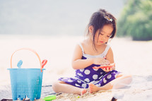 a girl on a beach playing with sand toys 