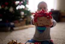 a child holding out a Christmas present 