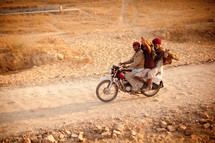 three men on a motorcycle on a dirt road in Pushkar, India