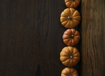 row of orange mini pumpkins on wood 