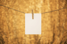 A blank notecard pinned on a line with a clothespin.