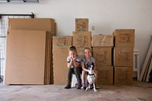children and a dog next to moving boxes 