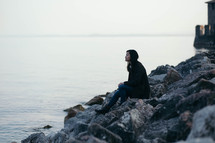 woman sitting on rocks near the ocean 