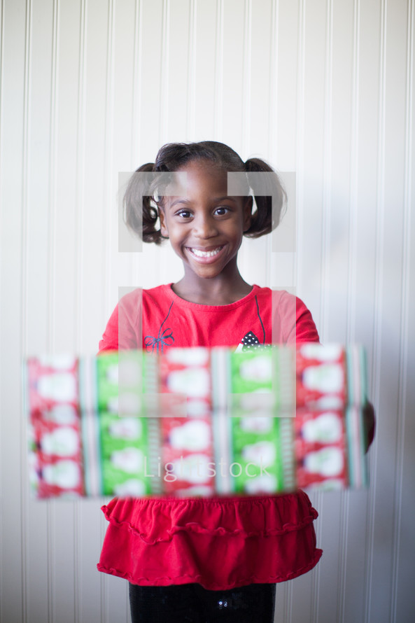a girl child holding Christmas present 