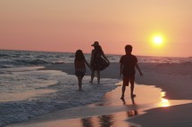 a family walking on a beach at sunset 
