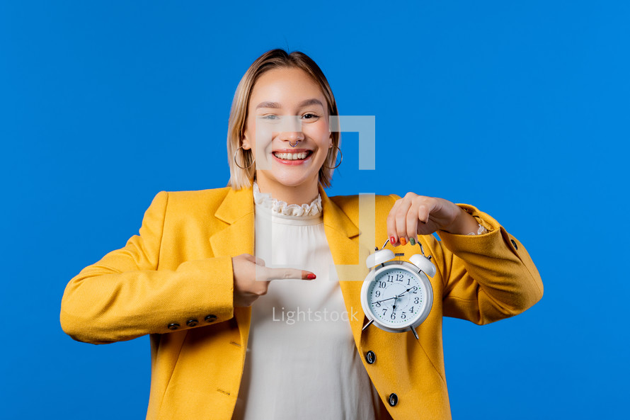 Happy student holding alarm clock