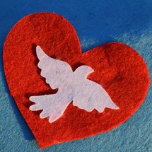 a red felt heart with a white dove 