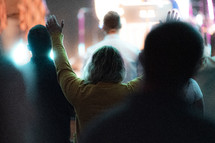 woman at a worship service with hands raised 