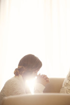woman praying by couch early in the morning
