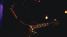 Guitarist playing on a dark stage.