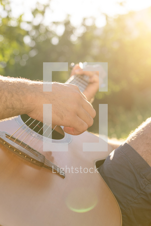 man strumming a guitar in warm sunlight 