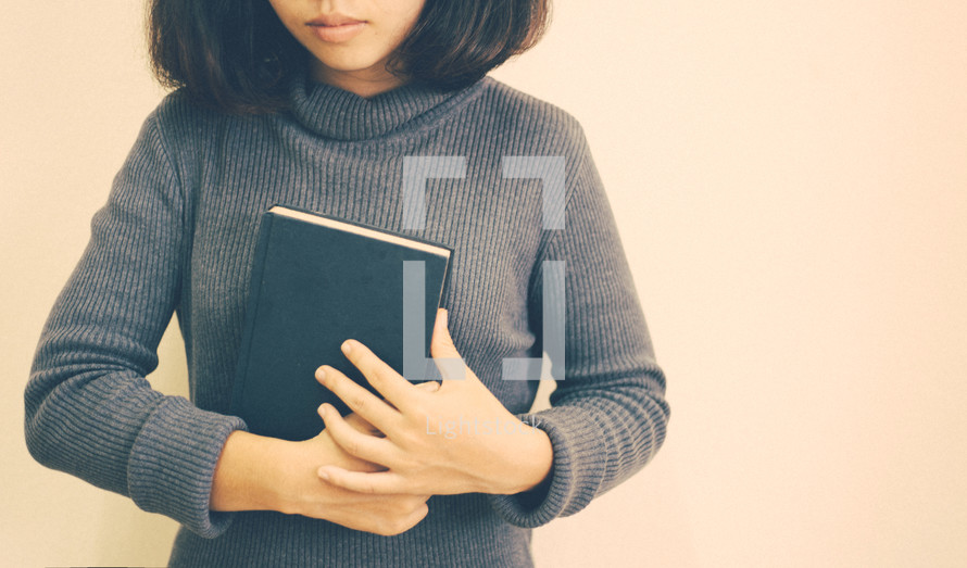 a woman holding a Bible close to her heart 