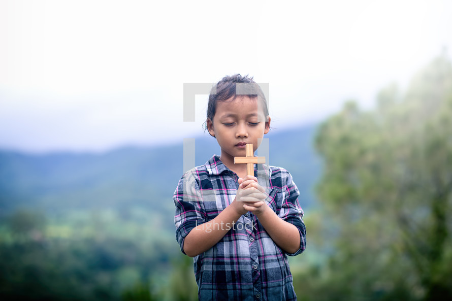 a child holding a cross outdoors 