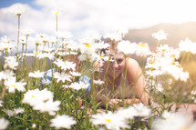 Smiling woman laying in a field of daisies.
