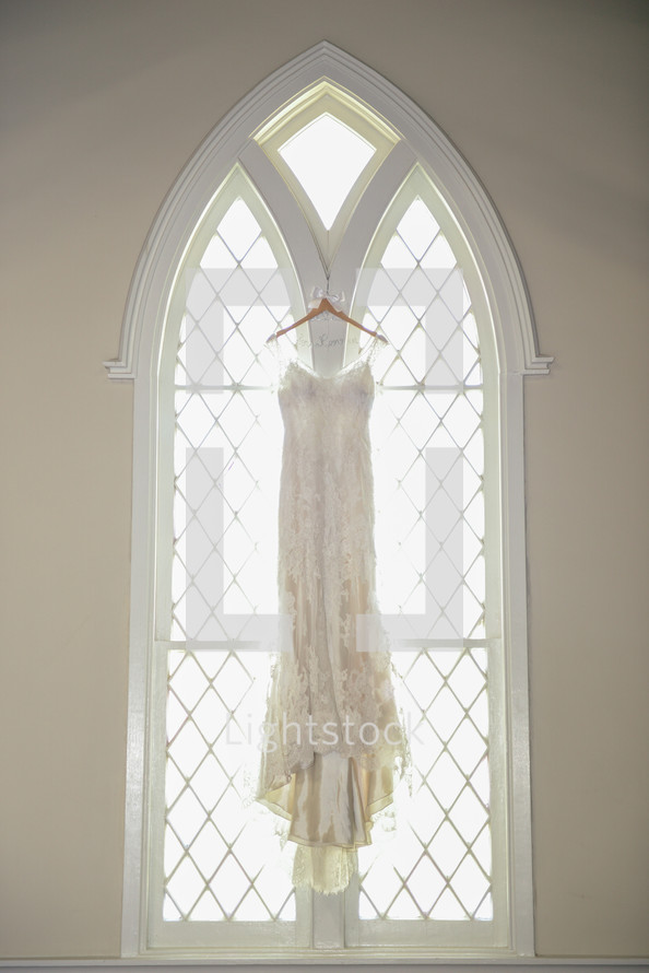 wedding dress hanging in a church window 