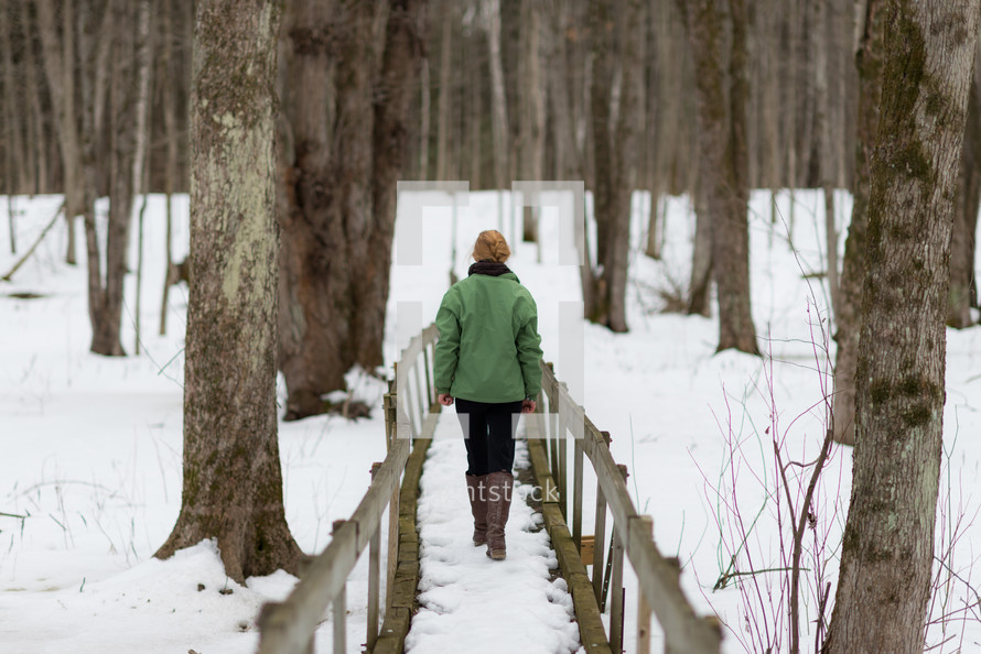 a teen girl walking on a bridge outdoors in winter snow 