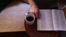 man reading a Bible with a cup of coffee 