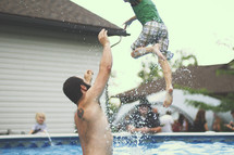 a man tossing a boy child in a pool 