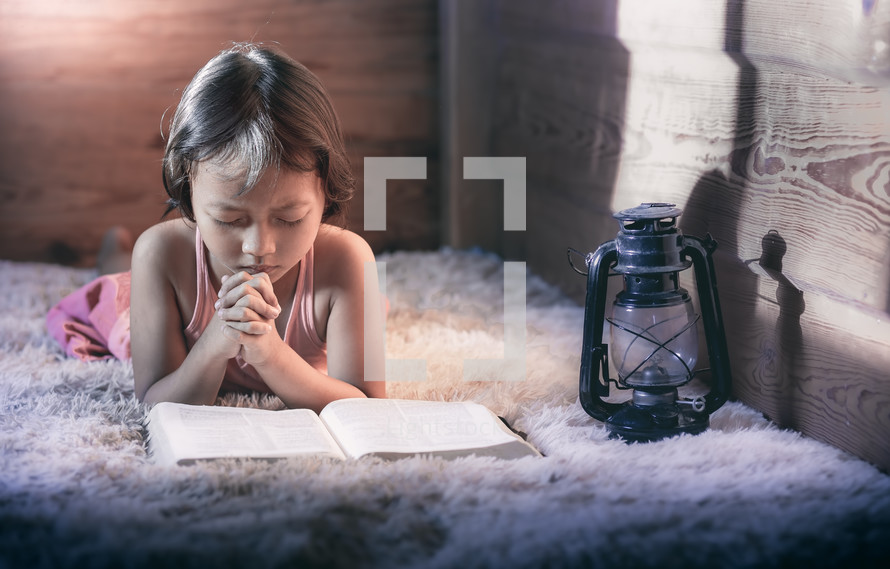 a child reading a Bible and praying 