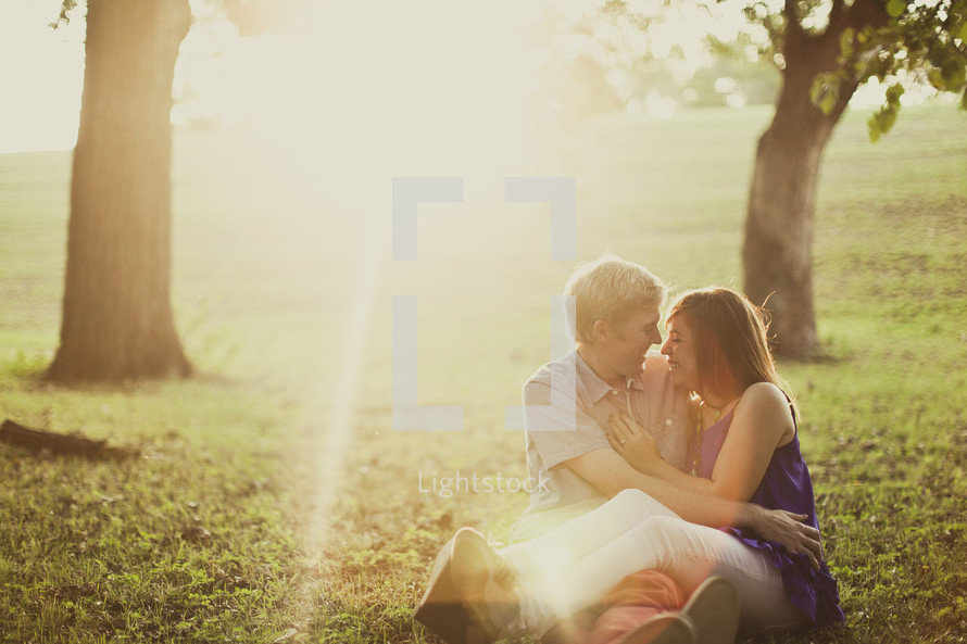 couple in an embrace sitting on the grass