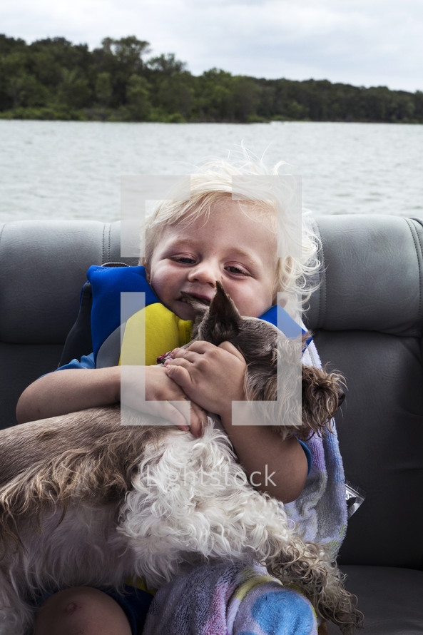 child hugging a dog on a boat