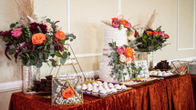 dessert table and wedding cake surrounded by floral display and  cupcakes at wedding event