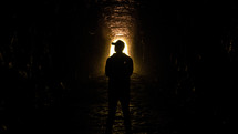 man in cave surrounded by light and shadow