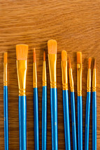 blue and gold paint brushes on  golden wood