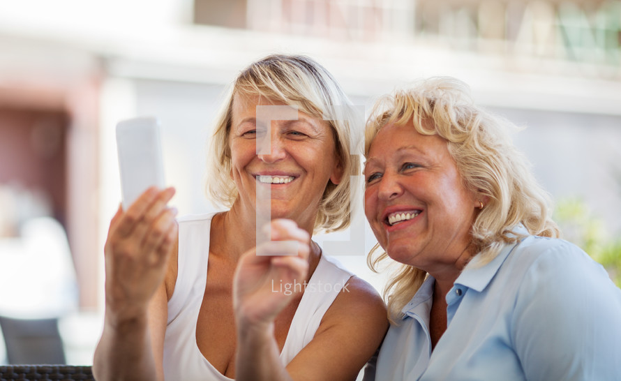 Modern mature women making happy mobile selfie