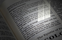 Beaming words "through Christ" on page of open Bible.